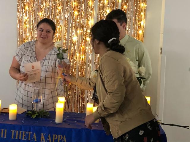 A new PTK member receives a white rose during the Induction Ceremony.
