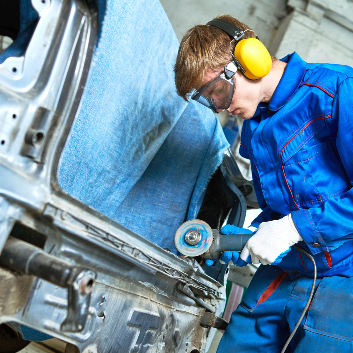 collision repairs service. mechanic grinding car body by grinder