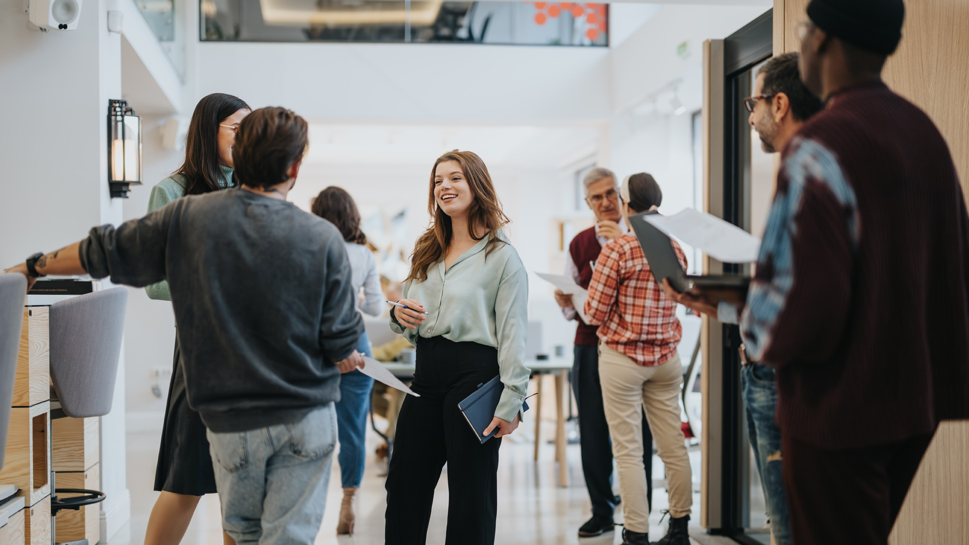 Businesspeople in a modern office space are engaging in a relaxed, informal networking session, exuding a friendly and collaborative atmosphere.