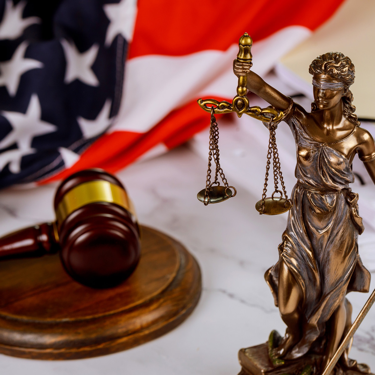 Figure of Justice holding the scales of justice with gavel on a law paper documents US flag