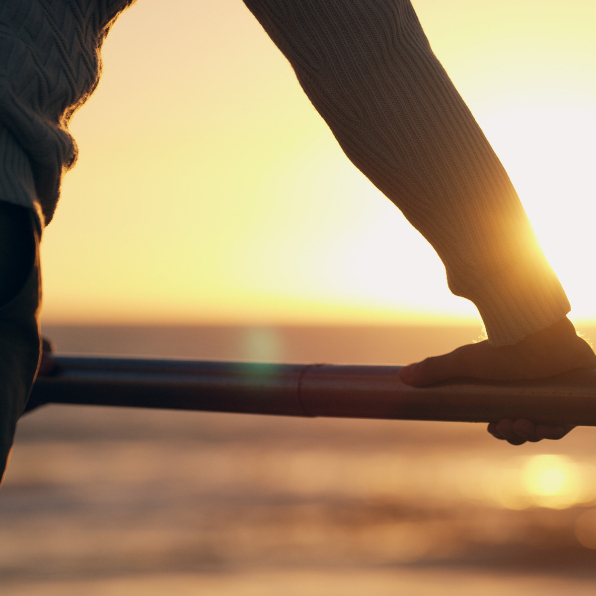 Hand, railing and reflection at beach, sunset and promenade in summer with blur