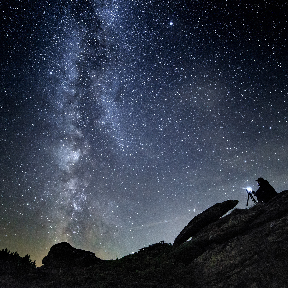 Photographer night sky in mountains with camera in tripod
