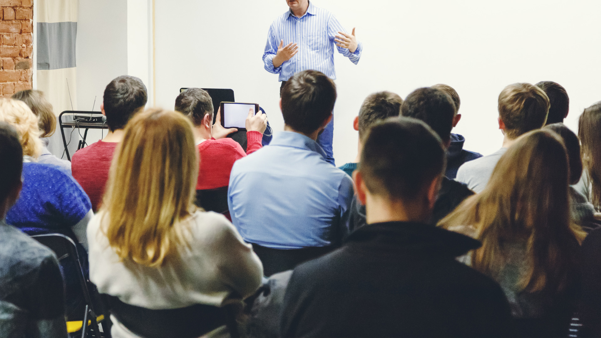 People listening to a presenter speaking at a workshop