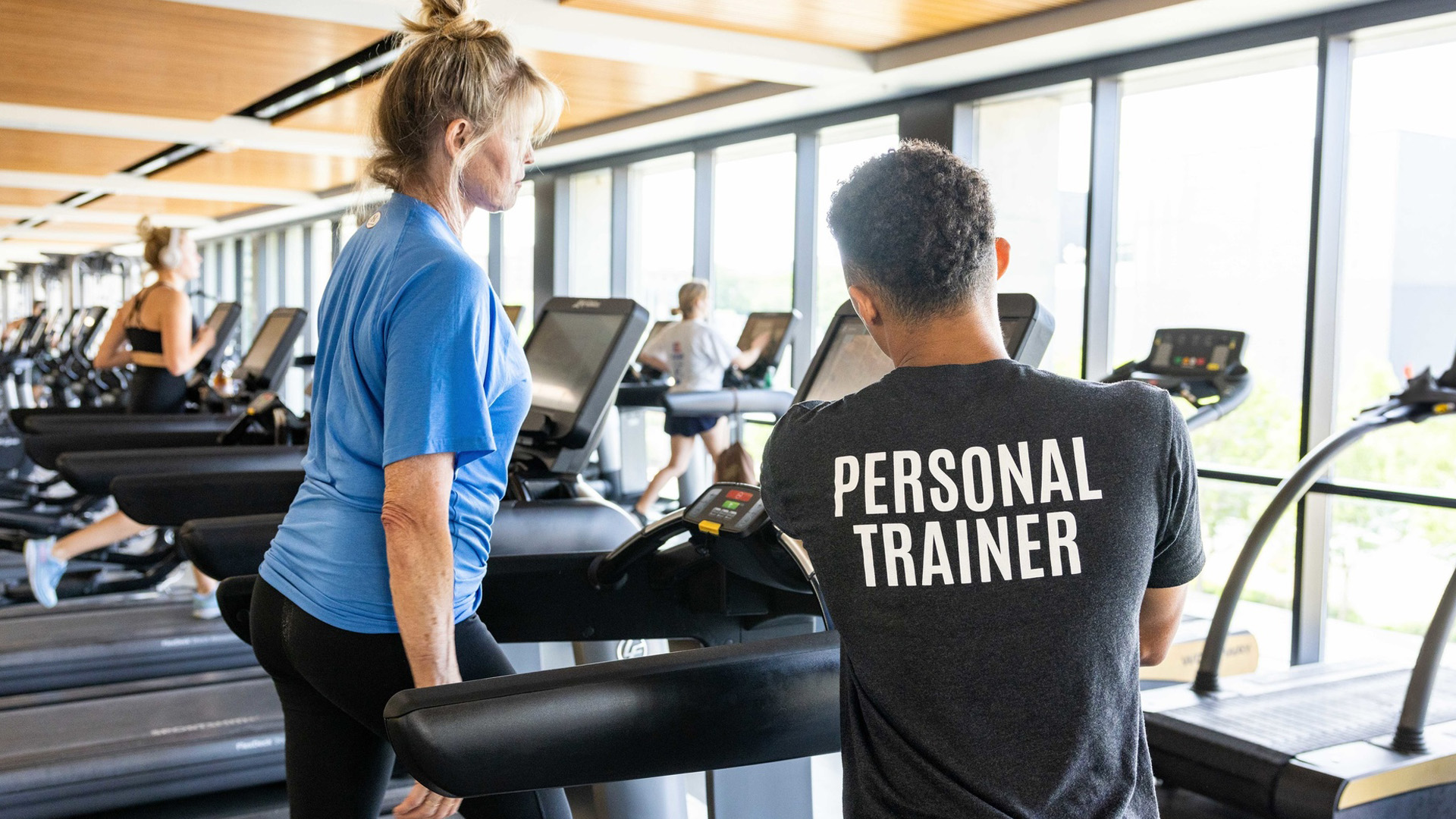 personal trainer assisting  a woman on a treadmill
