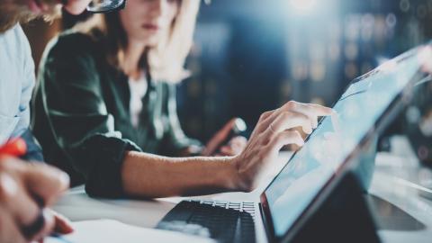 two people sitting in front of laptop, pointing and talking