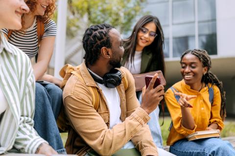 Students engaged in lively discussion on campus lawn during warm afternoon