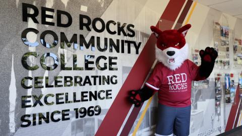 RRCC Mascot Copper next to sign "Red Rocks Community College Celebrating Excellence Since 1969"