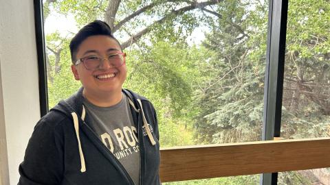 A person standing in front of a window smiles.