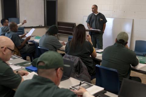 person in a grey uniform leading a class