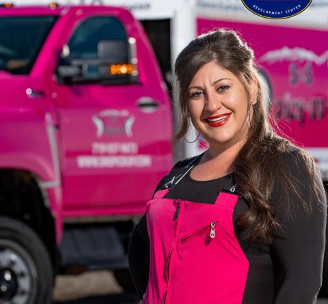 Employee in a pink uniform in front of a pink truck
