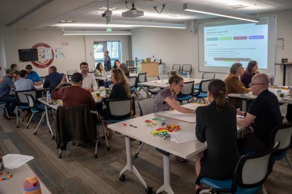 A room full of people sitting and engaging with each other at tables.