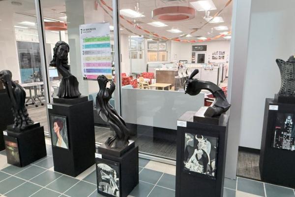 five sculptures on black stands with a picture of who they depict below them.