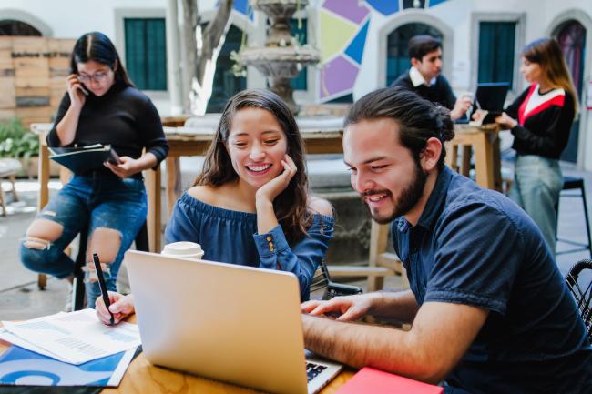 students sitting outside using laptops
