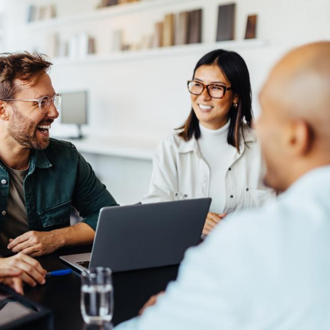 group of business people sitting around table looking at laptop