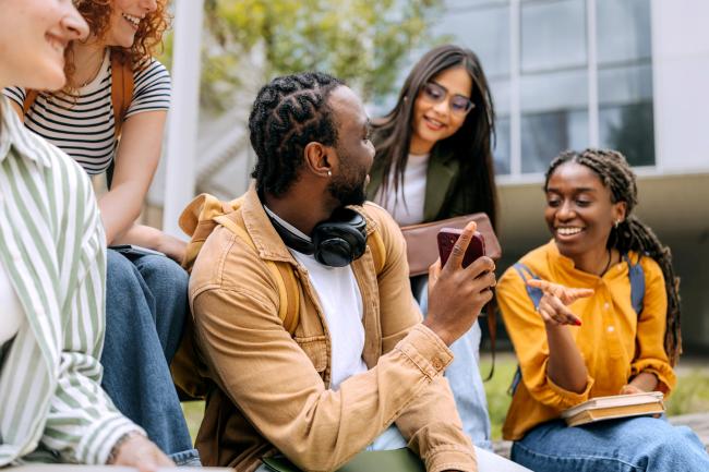 Students engaged in lively discussion on campus lawn during warm afternoon