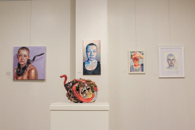 2022 Alumni Art Exhibit - 4 portrait paintings and a sculpture in front