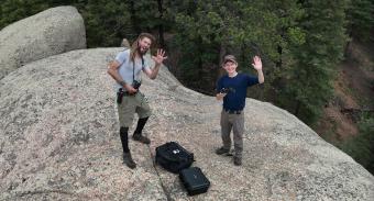 Bradley Harz and teammate on a boulder with a drone