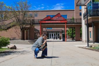 A person poses in front of the RRCC main entrance sign