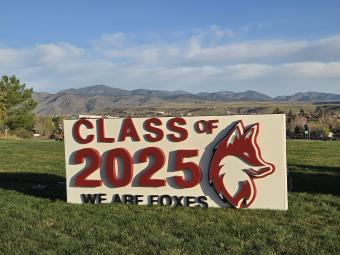 A white large sign that has red lettering that says Class of 2025, We are foxes