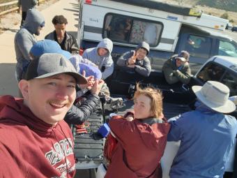 Students gathered around the bed of a pickup truck with a robot 