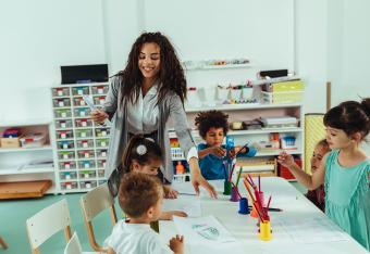 early childhood education teacher passing out supplies to students