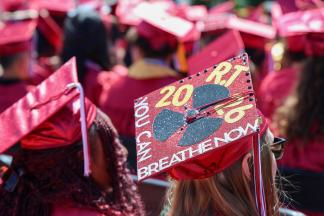 A sea of red graduation caps. One reads You can Breathe Now.