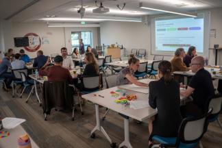 A room full of people sitting and engaging with each other at tables.