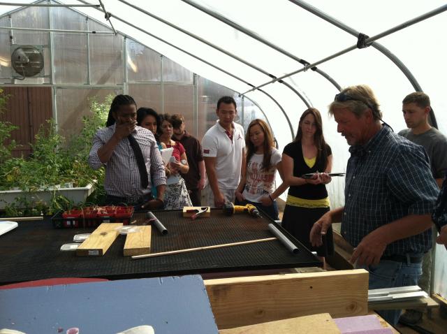 Students in greenhouse talking with groundskeeper