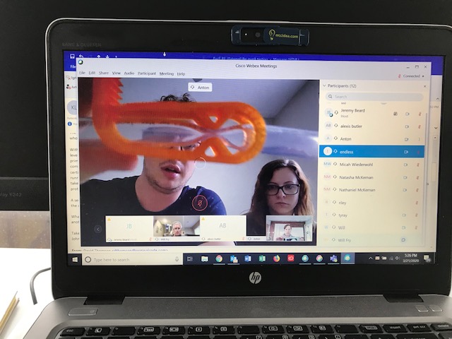Video conference on computer with student holding up 3D printed mockup valve.